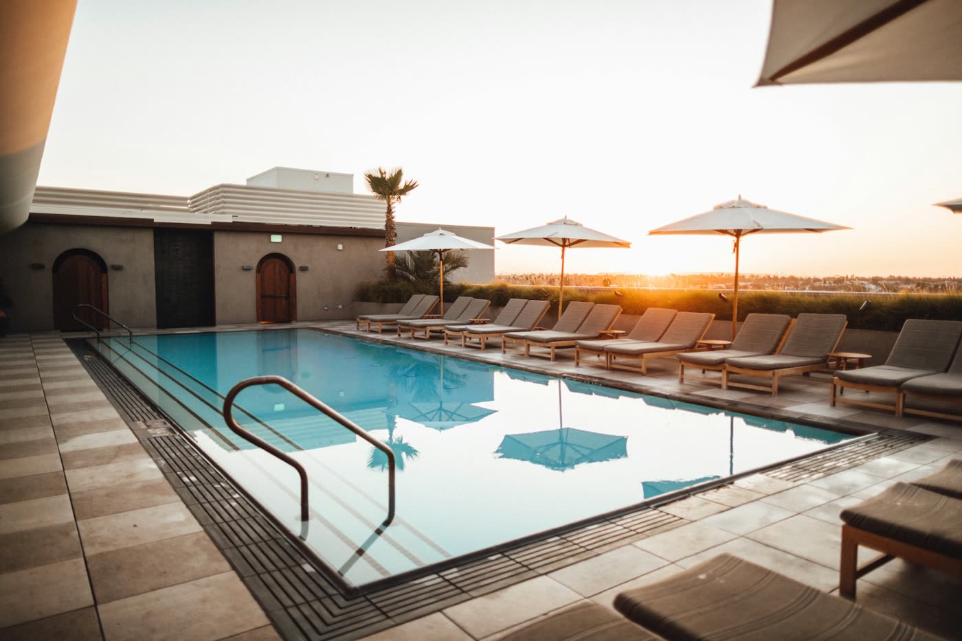 Piscine avec plage et transats au coucher du soleil, aménagement Piscine Pro en Vendée